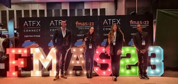 Four members of the Inbound FinTech team in attendance at the Finance Magnates Africa Summit 2023, standing in front of a colourfully illuminated 3D sign reading “FMAS23”